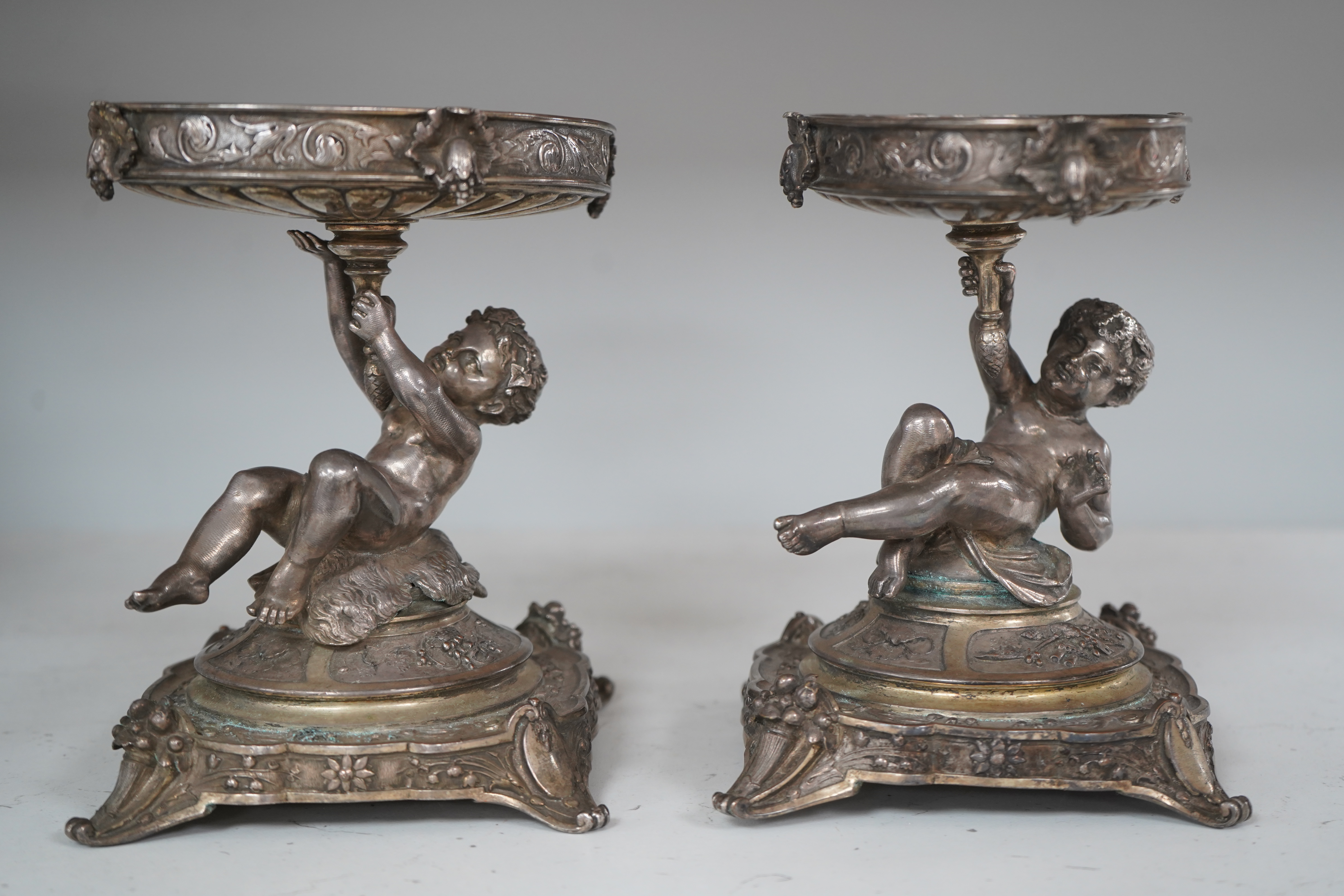 A pair of early 20th century Elkington & Co. silver plated ‘putti’ stands, 17cm. Condition - fair to good